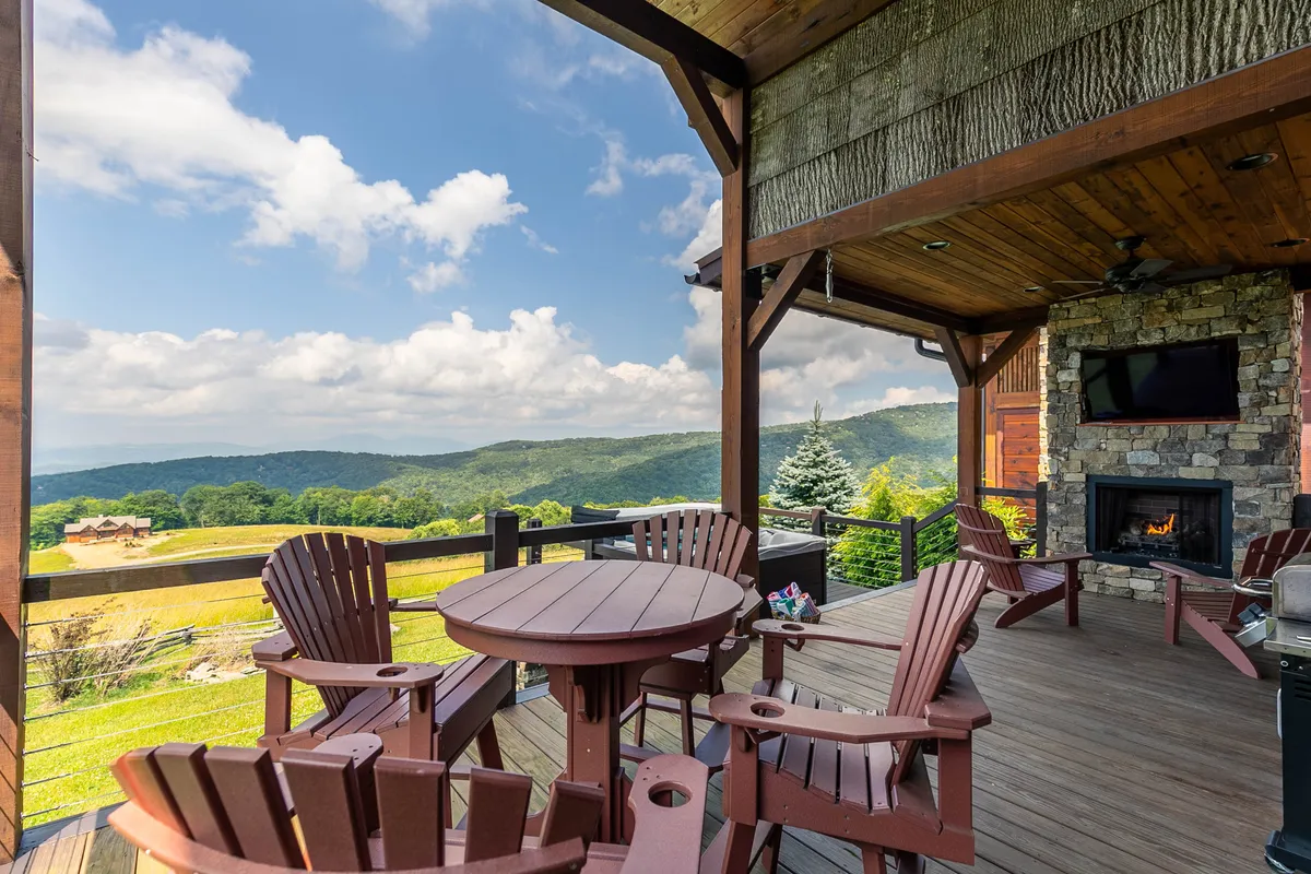 A spacious wooden deck with mountain views, outdoor seating, and a fireplace. The area offers plenty of room for families and pets to gather, play, or simply relax. The wide-open setting connects the indoors with the outdoors, making it easy for pets and owners to move freely.